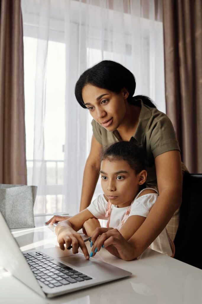 A mother helps her daughter with online learning at home, fostering education and togetherness.